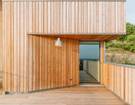 Parte della facciata di un edificio rivestita con pannelli verticali in legno di larice naturale.  | © SMV Costruzioni srl