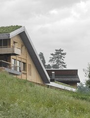 In un prato verde sorge una nuova casa con pareti in legno naturale e tetto verde | © Gustav Willeit