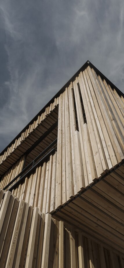 Ein Gebäude, das an der Außenfassade mit einer Schalung aus Lärchenholz-Leisten verkleidet ist | © Mariano Dallago